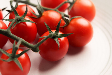 Freshly picked sprigs of ripe red cherry tomatoes on ceramic plate. Macro shot. 