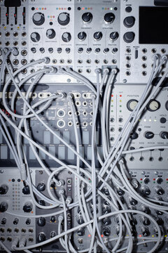 Closeup showing modular synthesizer with numerous patch cables connected to various input and output jacks, highlighting electronic music production equipment and signal routing