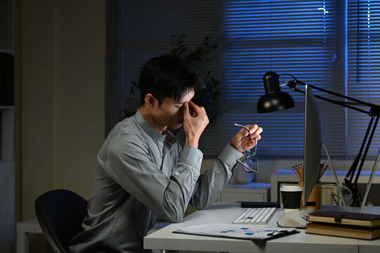 Tired, overworked and man with laptop, night or web designer with color sensitivity, sore or vision. Working late, employee and person with itching eyes, strain or poor lighting for glasses in office