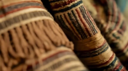 An extreme close-up of a rustic, hand-woven textile with colorful stripes and fringe, featuring a soft rack focus effect - Powered by Adobe