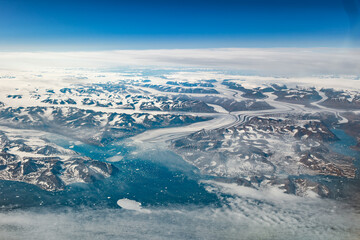 Fototapeta premium Aerial cockpit view of glacier flowing through mountains in Greenland