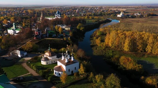 Kamenka river, autumn landscape of suzdal, churches and colorful trees at sunset