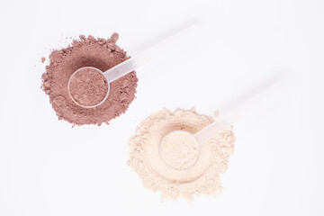Vanilla and chocolate protein powder in scoops on white background close-up top view.