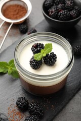 Tasty panna cotta with blackberries, mint and cocoa powder on grey table, closeup