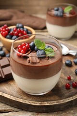 Delicious panna cotta with chocolate, berries and mint on wooden table, closeup