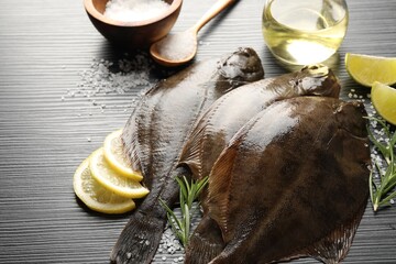 Fresh flounder fish, salt and products on black wooden table, closeup. Raw seafood