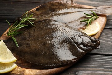 Fresh flounder fish, lemon and rosemary on wooden table, closeup. Raw seafood