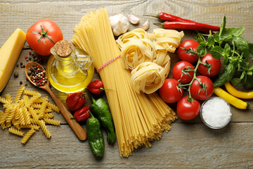 Different types of pasta and ingredients on wooden table, flat lay