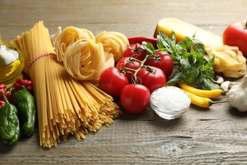 Different types of pasta and ingredients on wooden table, closeup