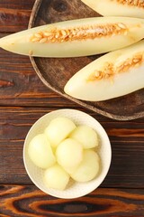 Cut ripe melon on wooden table, flat lay