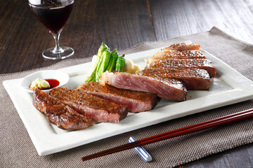 お箸で食べるカットした黒毛和牛サーロインステーキとワイン