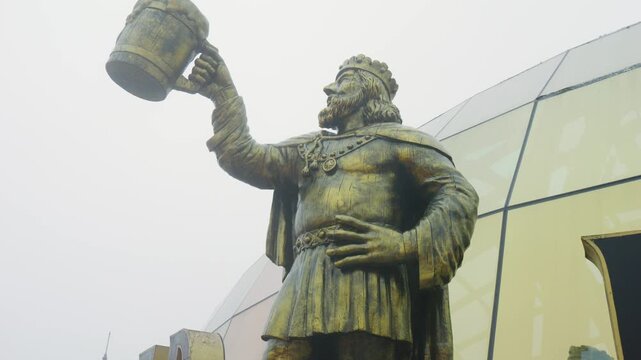 Bronze king statue raising beer stein against scenic ba na hills landscape, highlighting vietnamese tourist landmark with panoramic mountain backdrop