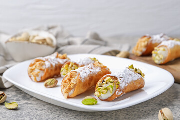 Delicious cannoli with ricotta cheese, peanuts, pistachios and powdered sugar on grey textured table, closeup