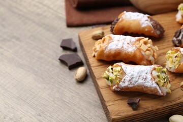 Delicious cannoli with ricotta cheese, peanuts, pistachios, chocolate and powdered sugar on wooden table, closeup. Space for text