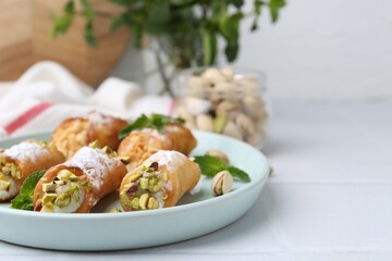 Delicious cannoli with cheese, nuts and mint on white table, closeup. Space for text