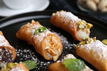Delicious cannoli with cheese, nuts, powdered sugar, chocolate and mint on table, closeup