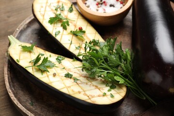 Halves of fresh eggplant, whole one, spices and parsley on wooden table, closeup
