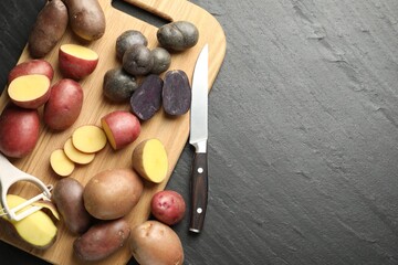 Different types of potatoes, peeler and knife on black table, flat lay. Space for text