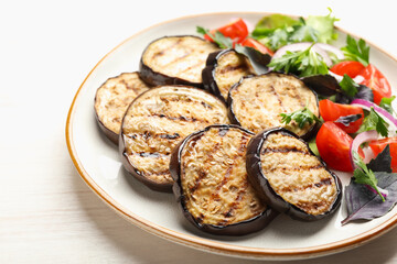 Grilled slices of eggplant with salad on white table, closeup