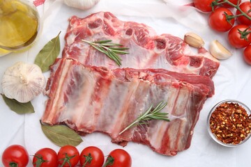 Fresh raw beef ribs, tomatoes and spices on white table, flat lay