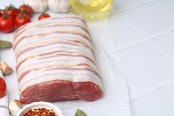 Piece of raw beef meat, tomatoes and spices on white tiled table, closeup. Space for text