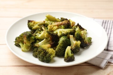 Tasty fried broccoli on light wooden table, closeup