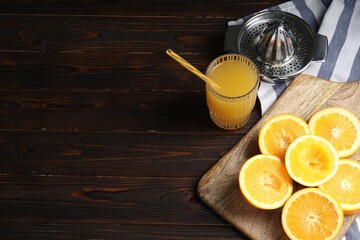 Freshly squeezed orange juice, fruits and juicer on wooden table. Space for text