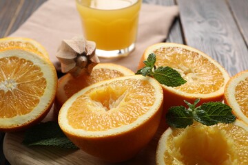 Freshly squeezed orange juice, fruits, mint, juicer and towel on wooden table, closeup