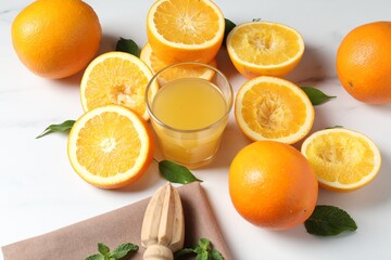 Freshly squeezed orange juice, fruits and juicer on white table, closeup