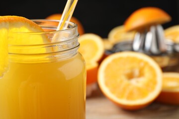 Freshly squeezed orange juice in mason jar and fruits on table, selective focus