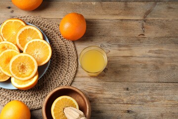 Freshly squeezed orange juice, fruits and juicer on wooden table, flat lay. Space for text