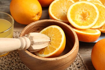 Squeezed oranges with juicer and glass of juice on wooden table, closeup