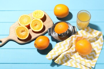 Freshly squeezed orange juice, fruits and juicer on blue wooden table, above view