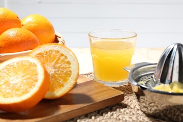 Freshly squeezed orange juice, fruits and juicer on table, closeup
