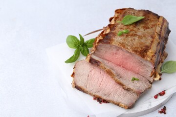 Delicious baked beef meat and spices on light table, closeup. Space for text