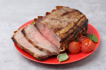 Delicious baked beef meat, tomatoes and basil on grey table, closeup