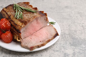 Delicious baked beef meat, tomatoes and rosemary on grey table, closeup. Space for text
