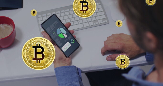 Holding smartphone, office worker reviewing live financial charts at white desk, with Bitcoin icons