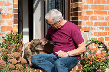 Mann genießt mit Dachshund die Herbstsonne vor der Haustüre © Heidi Bollich