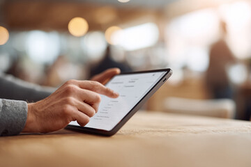 Closeup of hands using a digital tablet on a wooden table, suggesting productivity, modern lifestyle, and connectivity. Warm light, soft focus background.