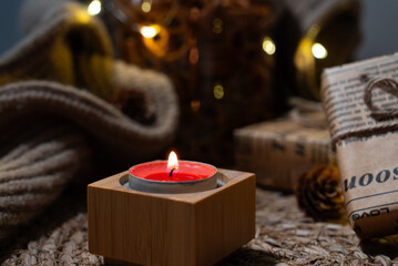Close-up red tealight on a rustic surface with blurred fairy lights and fall textures. Perfect for seasonal marketing and blogs.