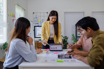 Group of confident asian business people point to graphs and charts analyze market data, balance sheet, account, net profit to plan new sales strategies to increase production capacity.	