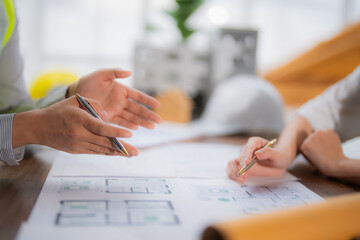 Two architects engaged in a detailed discussion about a building project, analyzing blueprints and collaborating on the design and planning of the construction in a modern office setting