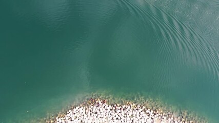 Bogura, Bangladesh - 21 August 2025: Aerial view of vibrant red chili peppers and colorful fabrics drying in the sun on a patterned stone surface, creating an eye-catching contrast.