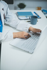 Middle aged female doctor working on laptop in doctor's room