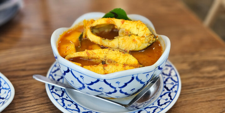 Thai spicy Sea bass fish with coconut shoot in yellow chili paste soup in Thai pattern plate