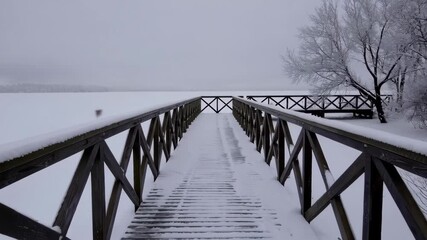Serene snowcovered bridge extends into misty winter landscape by a frozen lake - Powered by Adobe