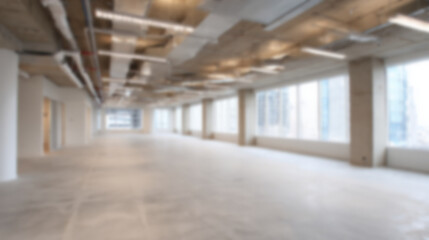 Blurred spacious empty office floor background, newly constructed commercial property. quiet interior shows concrete floor, ceiling, and windows with serene potential