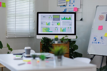 Laptop Computer, notebook ESG topic presentation on monitor, and eyeglasses sitting on a desk in a large open plan office space after working hours	