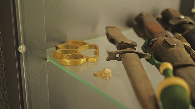 Close up of vintage brass knuckle and dagger with wood handle inside showcase